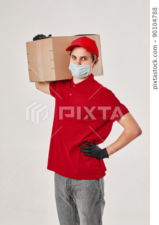 Delivery man employee in red cap face mask, empty cardboard box 90104788