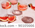 Champagne, rose sparkling wine or paloma cocktails in crystal glasses on pink background with pieces citrus . Refreshing beverage with grapefruit slice and mint. Summer drinks, selective focus 90105666