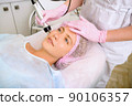 Image of a young beautiful woman dressed as a patient, lying on a couch in a cosmetology clinic. 90106357
