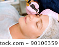 Image of a young beautiful woman dressed as a patient, lying on a couch in a cosmetology clinic. 90106359