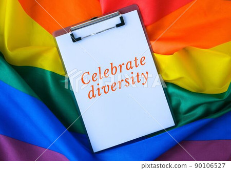 Rainbow flag with text CELEBRATE DIVERSITY message paper note. Rainbow lgbtq flag made from silk material. Symbol of LGBTQ pride month. Equal rights Rainbow flag with text CELEBRATE DIVERSITY message paper note. Rainbow lgbtq flag made from silk material. Symbol of LGBTQ pride month. Equal rights 90106527