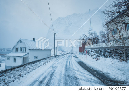 Fishing village with snow mountain on the road in snow storm on winter at Lofoten Islands 90106877