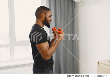 Man in a isolations. Guy training in a room. Man with dumbbells. Man in a isolations. Guy training in a room. Man with dumbbells. 90108083