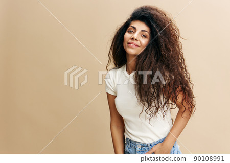 Gorgeous confident curly Latin female look at camera, crossing hands on the chest. Copy space for clothing fashion brands, free place for your ad. Studio shoot isolated over pastel beige background Gorgeous confident curly Latin female look at camera, crossing hands on the chest. Copy space for clothing fashion brands, free place for your ad. Studio shoot isolated over pastel beige background 90108991