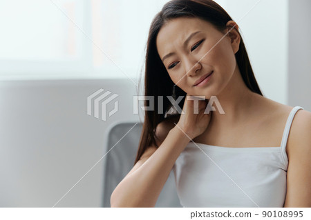Neck pain. Suffering from fibromyalgia tanned beautiful young Asian woman rubbing massaging tensed muscles at home interior living room. Injuries Poor health Illness concept. Cool offer Banner Neck pain. Suffering from fibromyalgia tanned beautiful young Asian woman rubbing massaging tensed muscles at home interior living room. Injuries Poor health Illness concept. Cool offer Banner 90108995