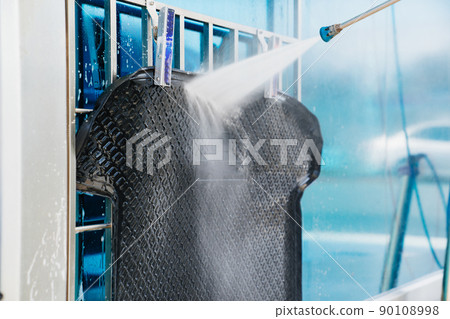 self-service car wash. a person washes the car mat from a hose. self-service car wash. a person washes the car mat from a hose. 90108998