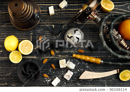 Arabic hookah with a tobacco flavor of a mixture of lemon. Top view of a dark wooden background 90109114