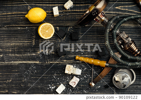 Arabic hookah with a tobacco flavor of a mixture of lemon. Top view of a dark wooden background Arabic hookah with a tobacco flavor of a mixture of lemon. Top view of a dark wooden background 90109122