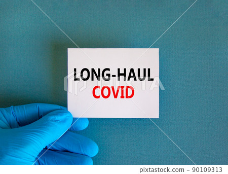 COVID-19 long-haul covid symptoms symbol. White card with words long-haul covid. Doctor hand, beautiful blue background, copy space. Medical, COVID-19 long-haul covid symptoms concept. 90109313