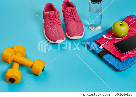 Healthy concept, diet plan with sport shoes and bottle of water and dumbbells on blue background, healthy food and exercise concept 90109433