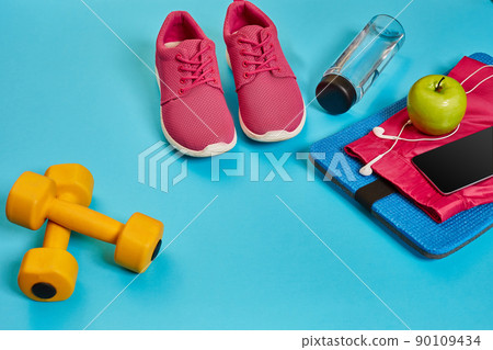 Healthy concept, diet plan with sport shoes and bottle of water and dumbbells on blue background, healthy food and exercise concept 90109434
