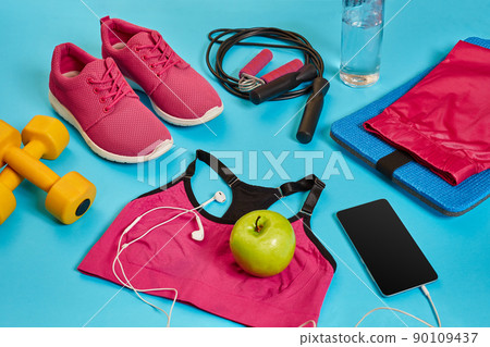 Flat lay of dumbbell, bottle of water, jump rope and sneaker, sport equipments, fitness items, top view 90109437