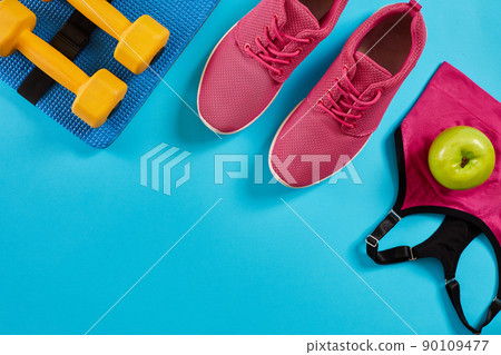 Athlete's set with female clothing and dumbbells on bright blue background Athlete's set with female clothing and dumbbells on bright blue background 90109477