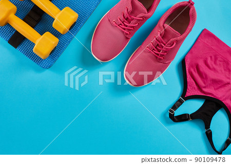 Athlete's set with female clothing and dumbbells on bright blue background Athlete's set with female clothing and dumbbells on bright blue background 90109478