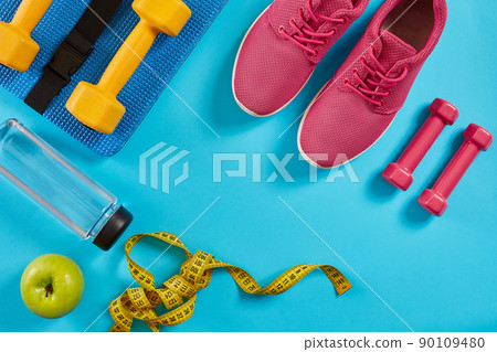 Athlete's set with female clothing, dumbbells and bottle of water on bright blue background 90109480