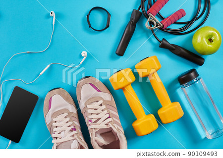 Athlete's set with female clothing, dumbbells and bottle of water on bright blue background Athlete's set with female clothing, dumbbells and bottle of water on bright blue background 90109493
