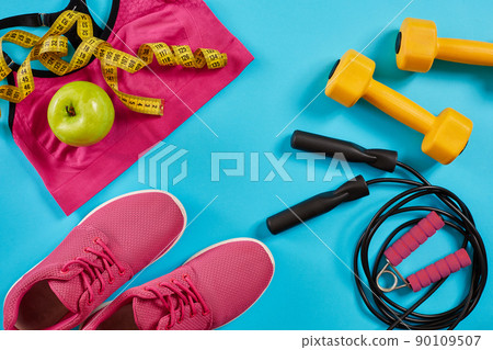 Athlete's set with female clothing, dumbbells and bottle of water on bright blue background 90109507
