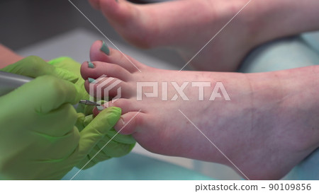 A professional pedicurist performs the procedure for removing old toenails. Girl in salon close-up. A professional pedicurist performs the procedure for removing old toenails. Girl in salon close-up. 90109856