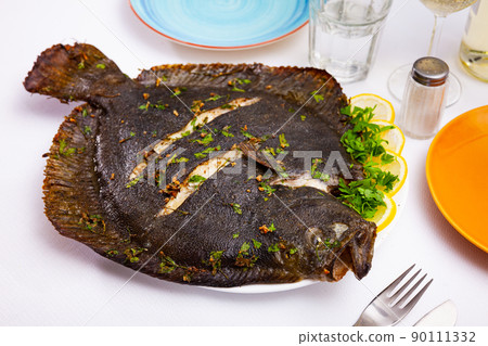 Baked flounder with parsley and lemon. Mediterranean cuisine closeup Baked flounder with parsley and lemon. Mediterranean cuisine closeup 90111332