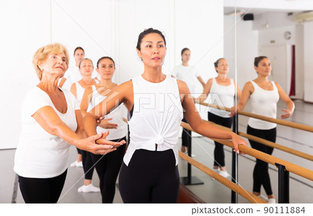 Elderly ballet instructor adjusting students form 90111884