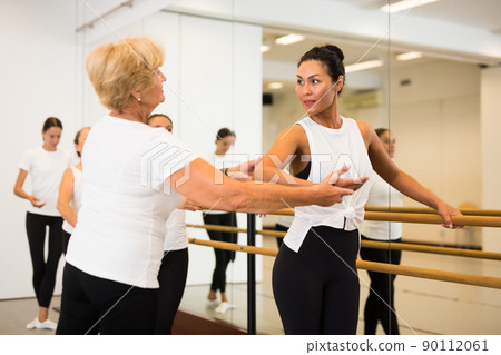 Elderly ballet instructor adjusting students form 90112061