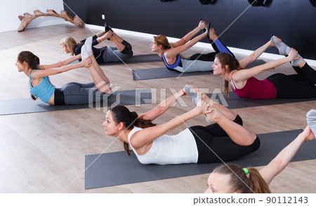 Women exercising yoga poses in fitness center Women exercising yoga poses in fitness center 90112143