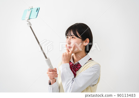 High school girls taking selfies with their smartphones High school girls taking selfies with their smartphones 90113483