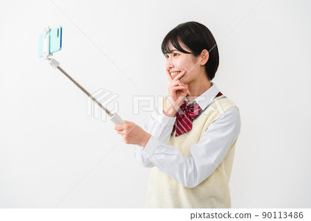 High school girls taking selfies with their smartphones High school girls taking selfies with their smartphones 90113486
