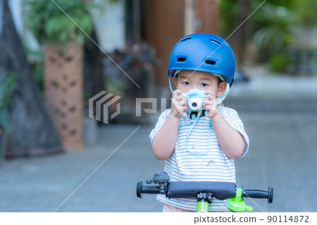 asian baby boy wearing Bike helmet plays with camera 90114872