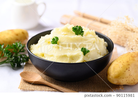Mashed potato with parsley in black bowl on white background 90115981