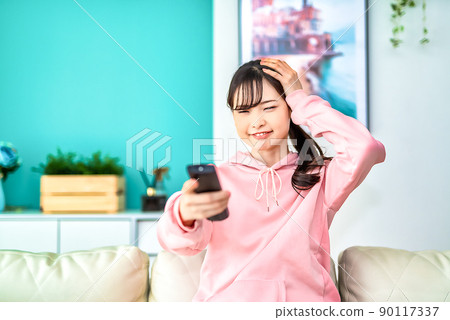 Surprised young woman watching TV Surprised young woman watching TV 90117337