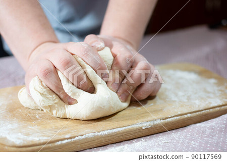 Knead the dough on a wooden board at home 90117569