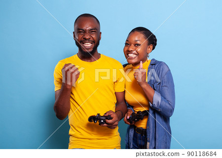 Cheerful people winning video games with controller on console in studio. Boyfriend and girlfriend playing online game with joystick to win, feeling happy and relaxed with leisure activity. Cheerful people winning video games with controller on console in studio. Boyfriend and girlfriend playing online game with joystick to win, feeling happy and relaxed with leisure activity. 90118684