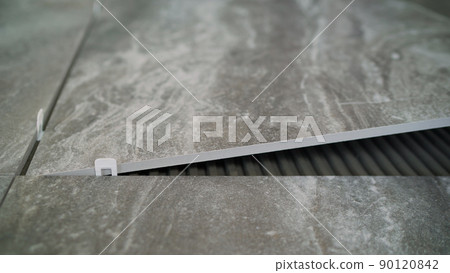 Renovating the floor. Construction workers laying tile over concrete floor using tile levelers, notched trowels and tile mortar.Laying floor ceramic tile. 90120842