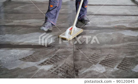 The tiler washes the tiles after work. A worker cleans the tiles on the floor after gluing. 90120845