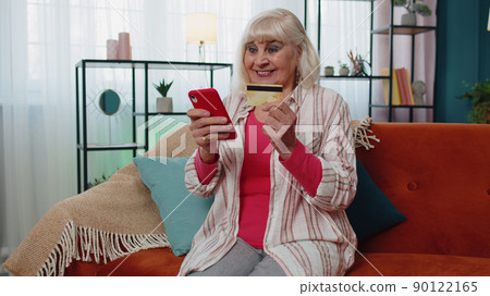 Senior woman hold credit card, entering its number into mobile phone, shopping online buying goods Senior woman hold credit card, entering its number into mobile phone, shopping online buying goods 90122165