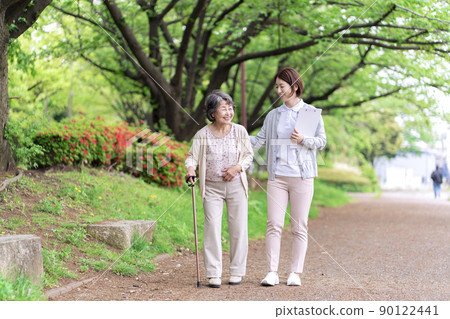 Rehabilitation of senior women and caregivers taking a walk in the park 90122441