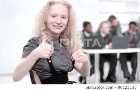 young female assistant showing thumb up standing in the office 90123133