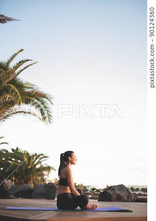 Young beautiful woman meditating outdoors at sunrise. Young beautiful woman meditating outdoors at sunrise. 90124360