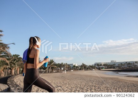 Beautiful fitness woman looking at the beach after training . Beautiful fitness woman looking at the beach after training . 90124362