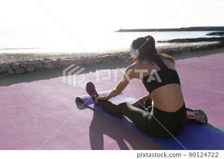 Beautiful girl stretching in front of the beach after exercising. Beautiful girl stretching in front of the beach after exercising. 90124722