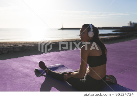 Beautiful caucasian girl resting in front of the beach after exercising. Beautiful caucasian girl resting in front of the beach after exercising. 90124724