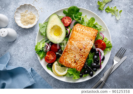 Grilled salmon fish fillet and fresh vegetable salad with tomato, red onion, black olives and avocado Grilled salmon fish fillet and fresh vegetable salad with tomato, red onion, black olives and avocado 90125358