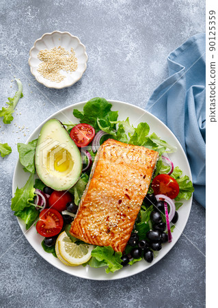 Grilled salmon fish fillet and fresh vegetable salad with tomato, red onion, black olives and avocado Grilled salmon fish fillet and fresh vegetable salad with tomato, red onion, black olives and avocado 90125359