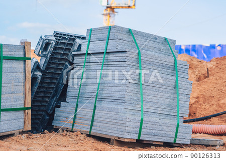 Industrial building cement pressed materials. Concrete block cement brick. Finished products on pallets compactly stacked wooden frame placed on construction site house, rope tape packed open air sky 90126313