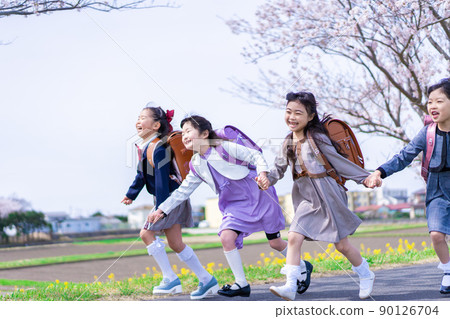 Elementary school girls carrying school bags on their backs and having fun going to school 90126704