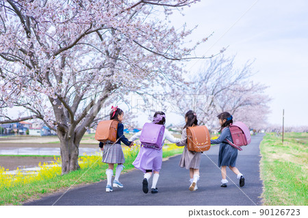 Elementary school girls carrying school bags on their backs and having fun going to school Elementary school girls carrying school bags on their backs and having fun going to school 90126723
