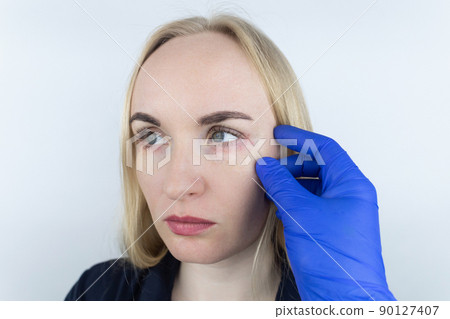 Allergy to cosmetics. The girl looks at the pimples around her eyes that appeared after using toxic cosmetics. Red spots on woman skin Allergy to cosmetics. The girl looks at the pimples around her eyes that appeared after using toxic cosmetics. Red spots on woman skin 90127407
