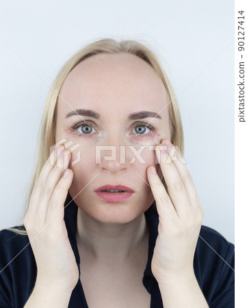 Allergy to cosmetics. The girl looks at the pimples around her eyes that appeared after using toxic cosmetics. Red spots on woman skin Allergy to cosmetics. The girl looks at the pimples around her eyes that appeared after using toxic cosmetics. Red spots on woman skin 90127414
