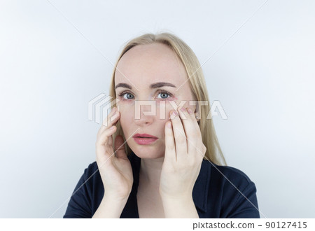 Allergy to cosmetics. The girl looks at the pimples around her eyes that appeared after using toxic cosmetics. Red spots on woman skin Allergy to cosmetics. The girl looks at the pimples around her eyes that appeared after using toxic cosmetics. Red spots on woman skin 90127415